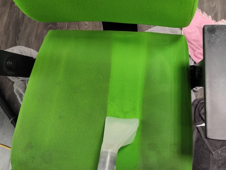 Zielone krzesło w trakcie prania tapicerki . Widać czysty pas.
